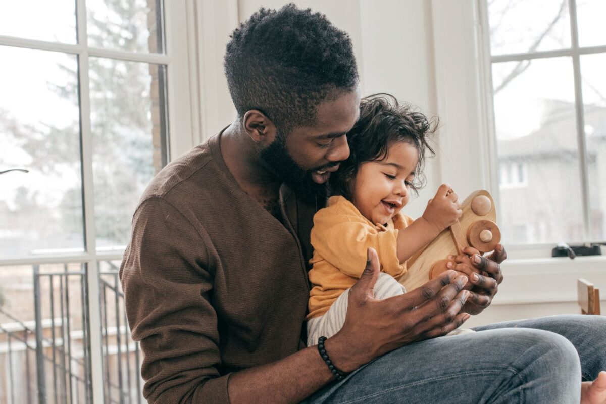 Father and child playing with wooden toy